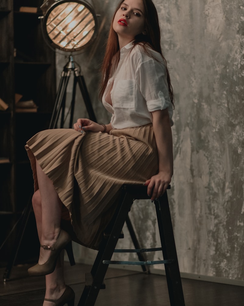 A woman in a crisp white shirt and camel pleated midi skirt