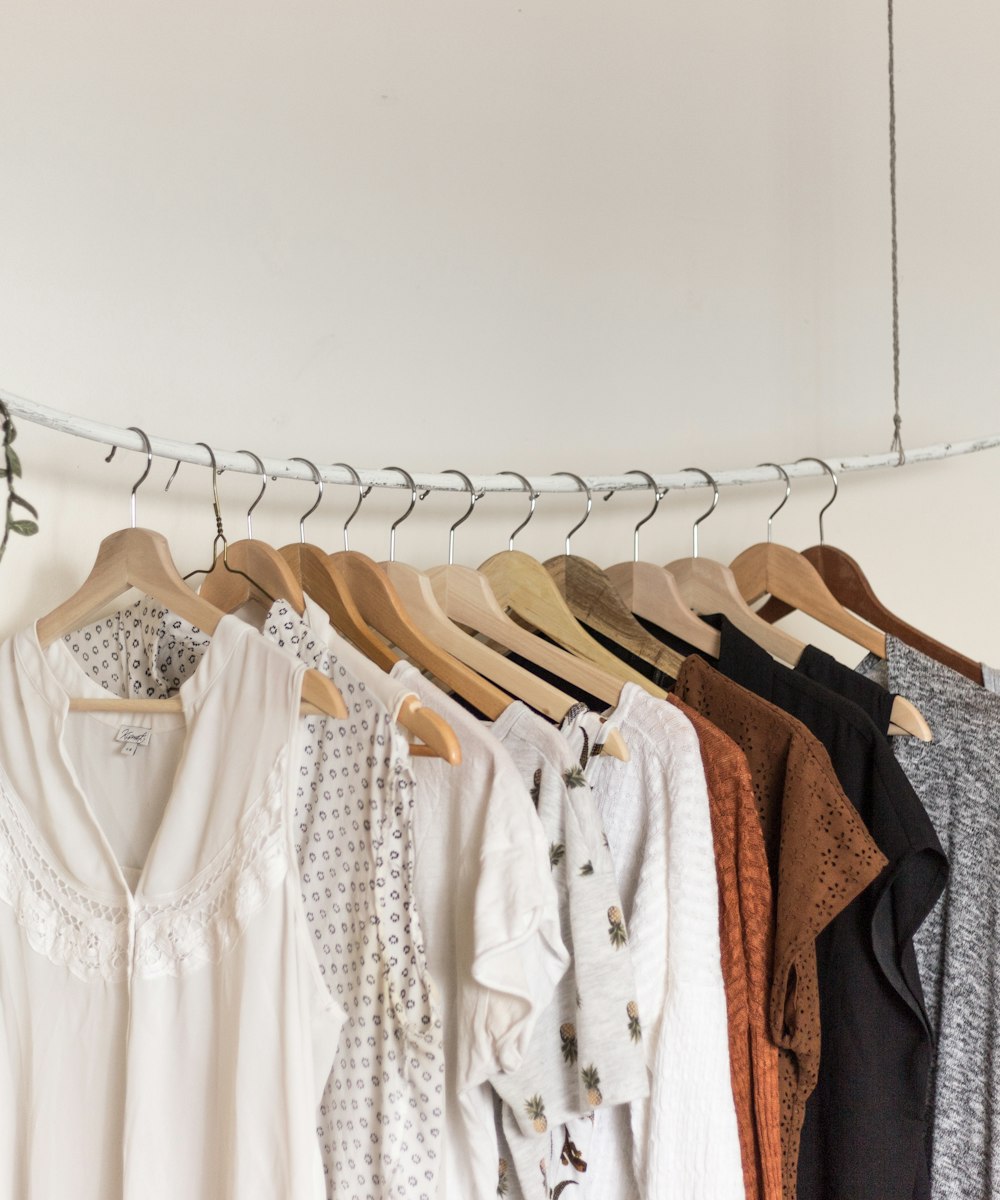 A rail of neutral-toned blouses on wooden hangers in a warm boutique