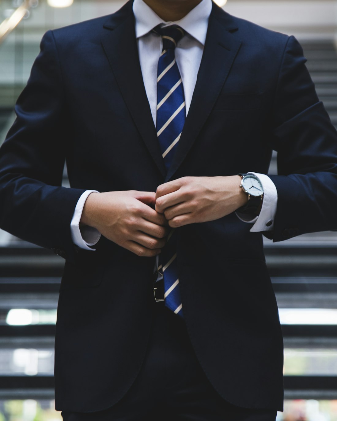 Man in a dark tailored suit adjusting his tie