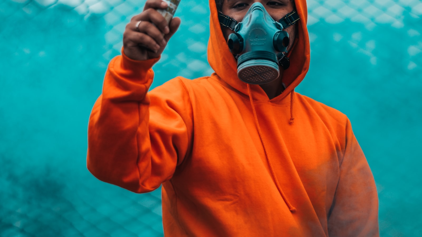 NOX Supply campaign — figure in a hooded top releasing teal smoke behind a chain-link fence