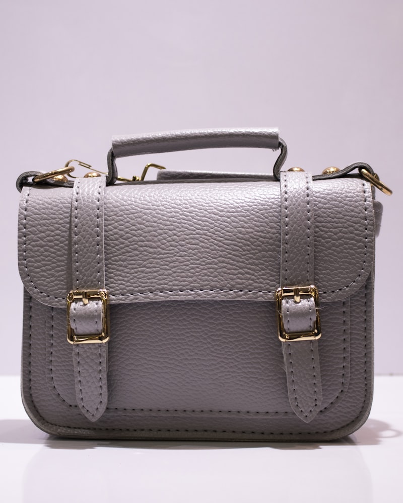 A structured tan leather handbag held by a model