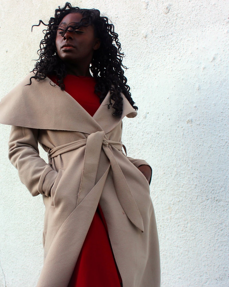A camel coat over tailored trousers on a model