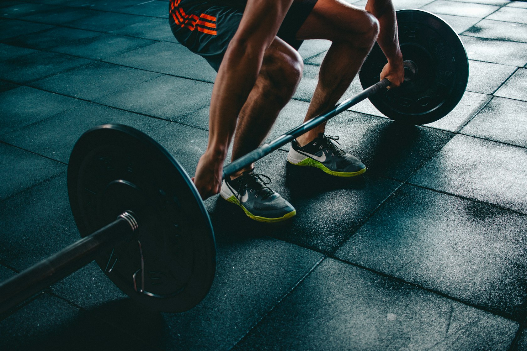 An athlete mid-lift in a dark gym, lit by neon-lime accents