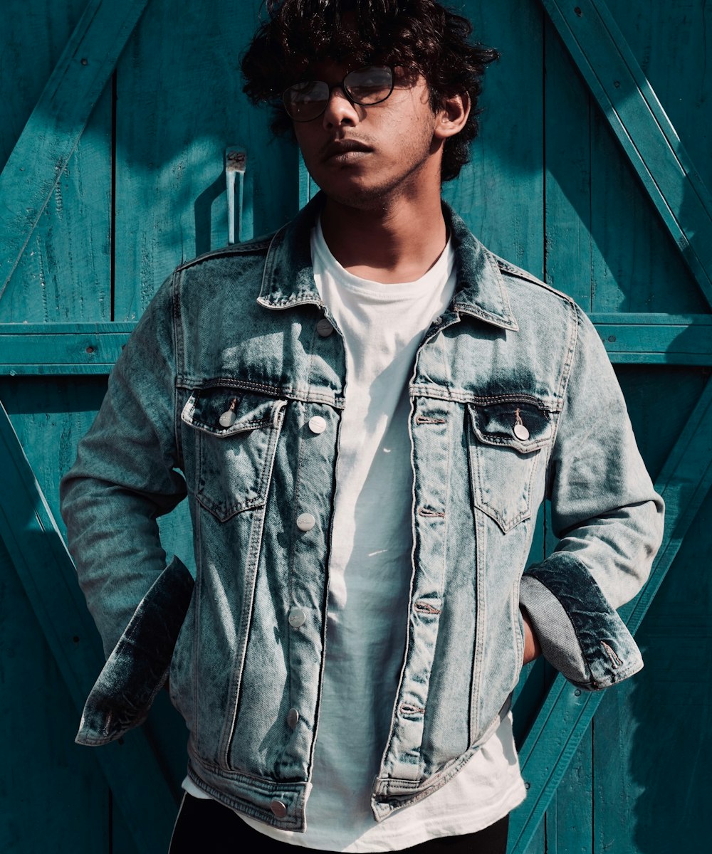 A man wearing a worn Ironloom denim trucker jacket against a weathered timber door