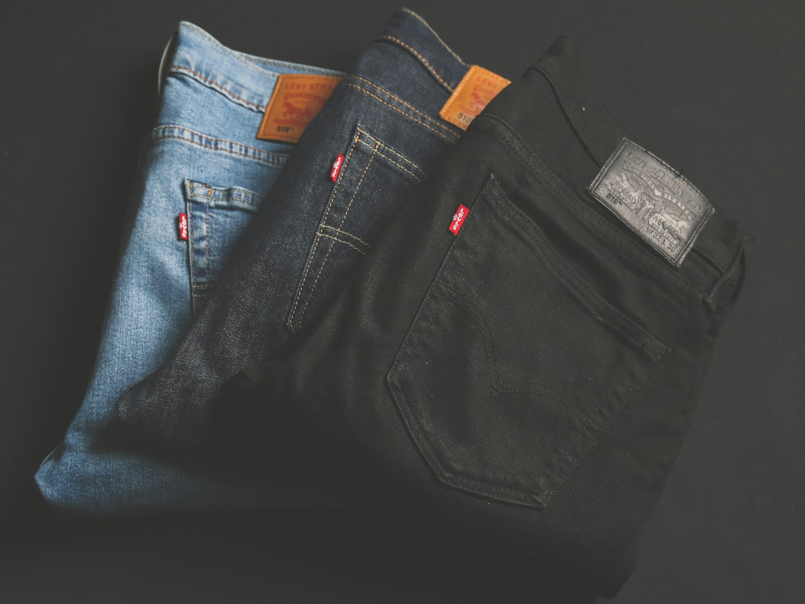 A stack of raw and rinsed Ironloom selvedge jeans with copper rivets and a leather patch