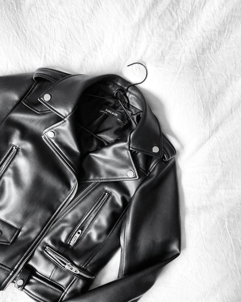 A black leather biker jacket laid flat