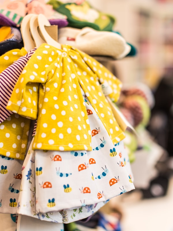 A rail of little folded baby clothes in cheerful prints