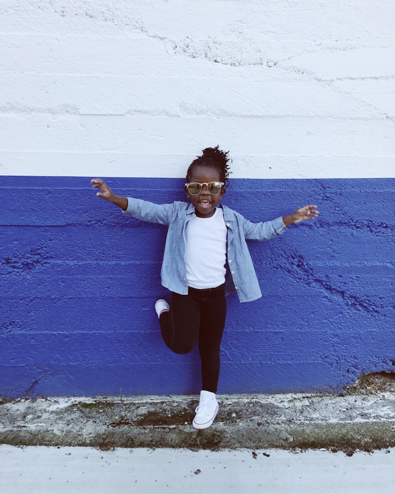 Toddler in a denim shirt against a bright blue wall