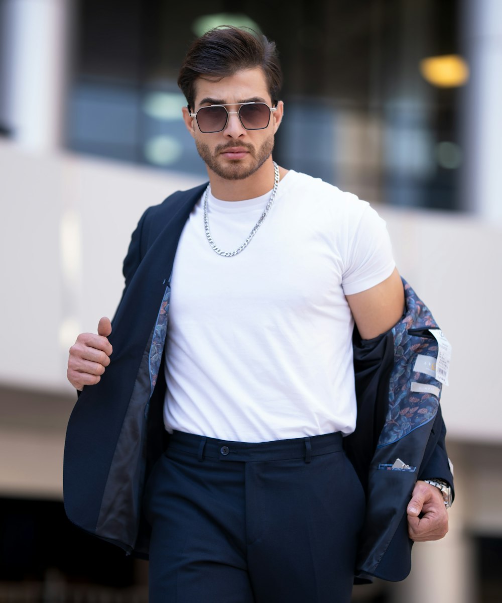 A man in a white shirt wearing gold Aether aviators on a city street