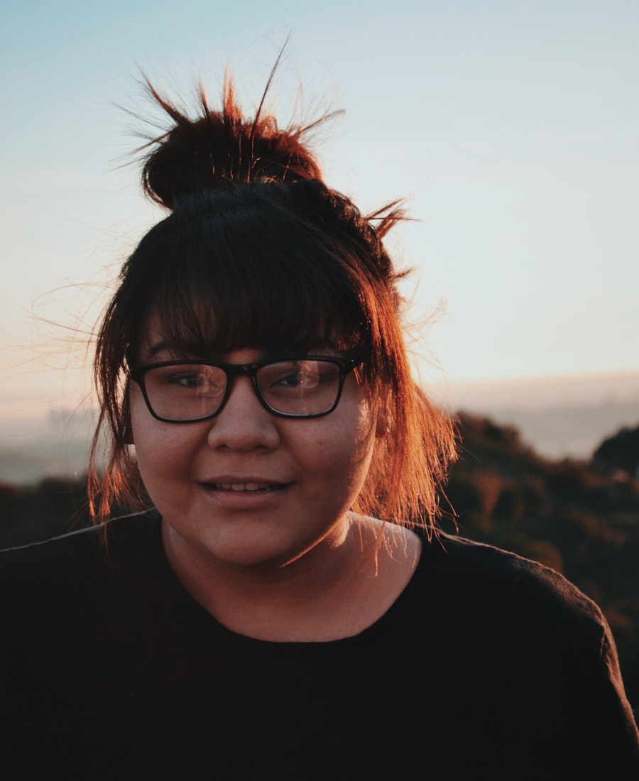 A person trying on round Aether optical frames against a blue wall