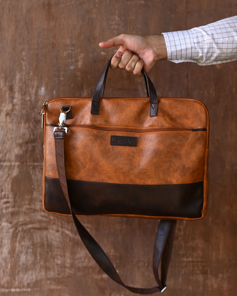 A two-tone leather crossbody bag held by hand