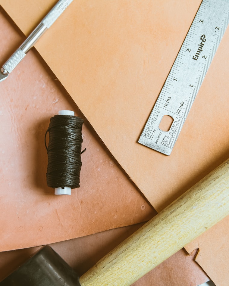 Vegetable-tanned leather with thread and tools on a workbench