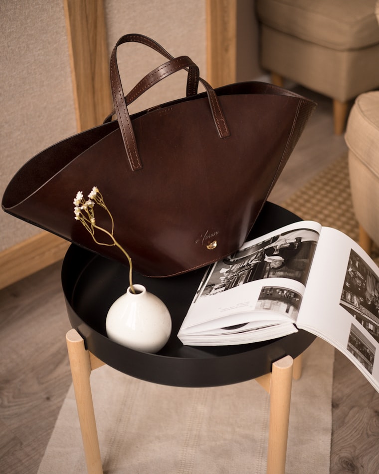 A structured leather tote styled on a side table with a book