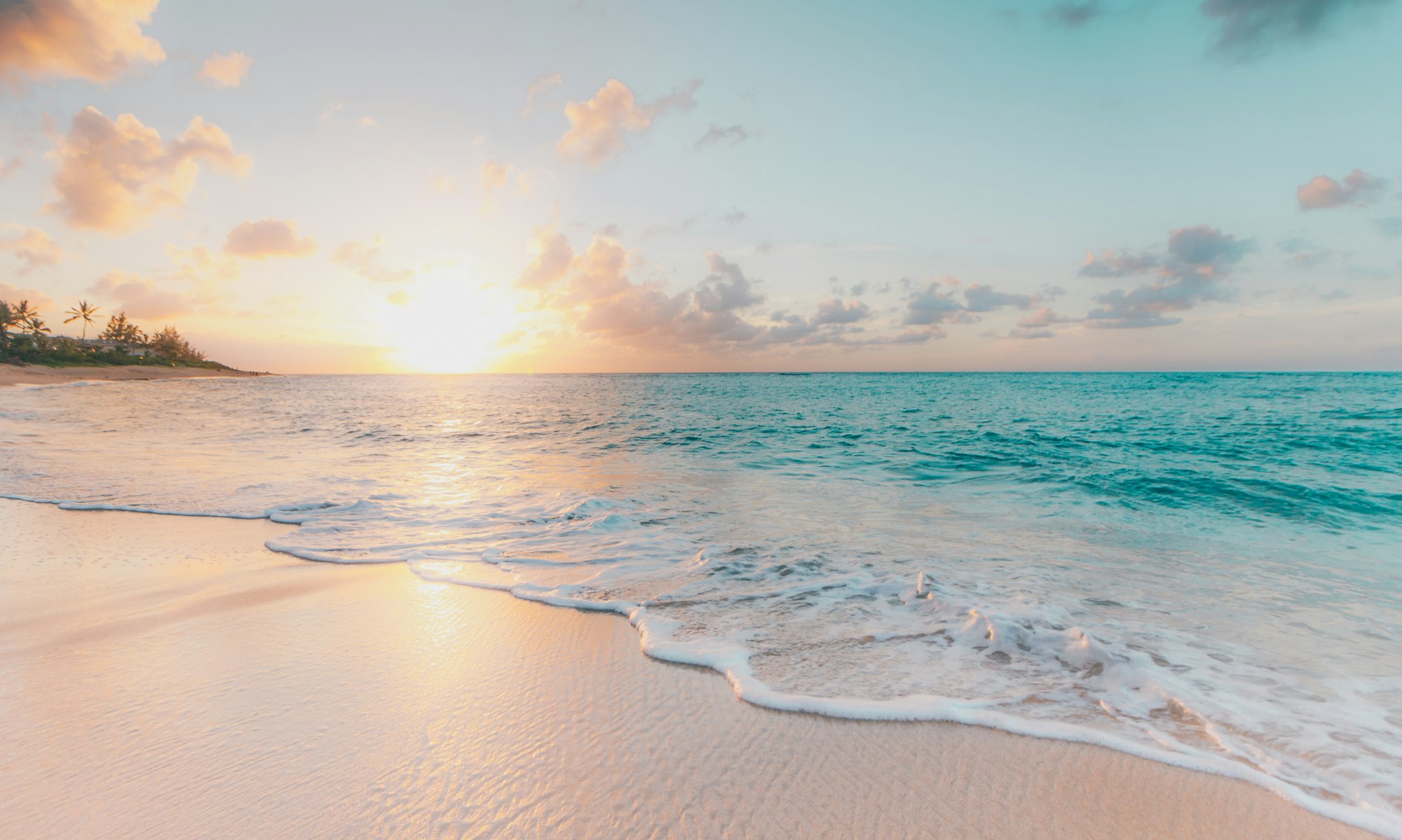 A quiet turquoise beach at golden hour with soft white surf