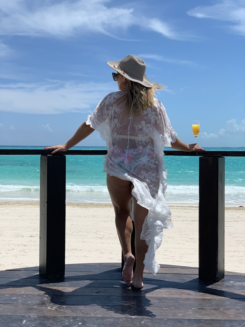 A model in a white lace beach coverup and hat by the sea