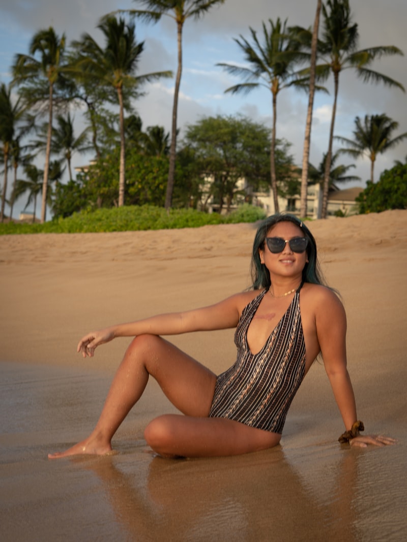 A model in a printed one-piece on the sand at sunset