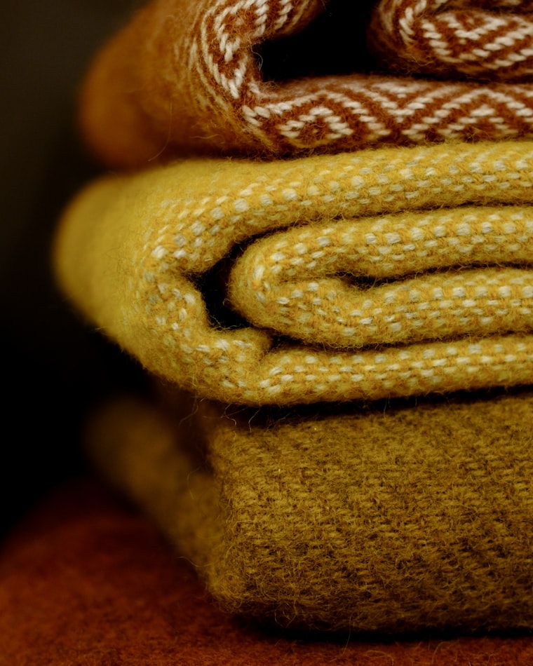 A stack of folded cashmere and wool knits in warm autumn tones