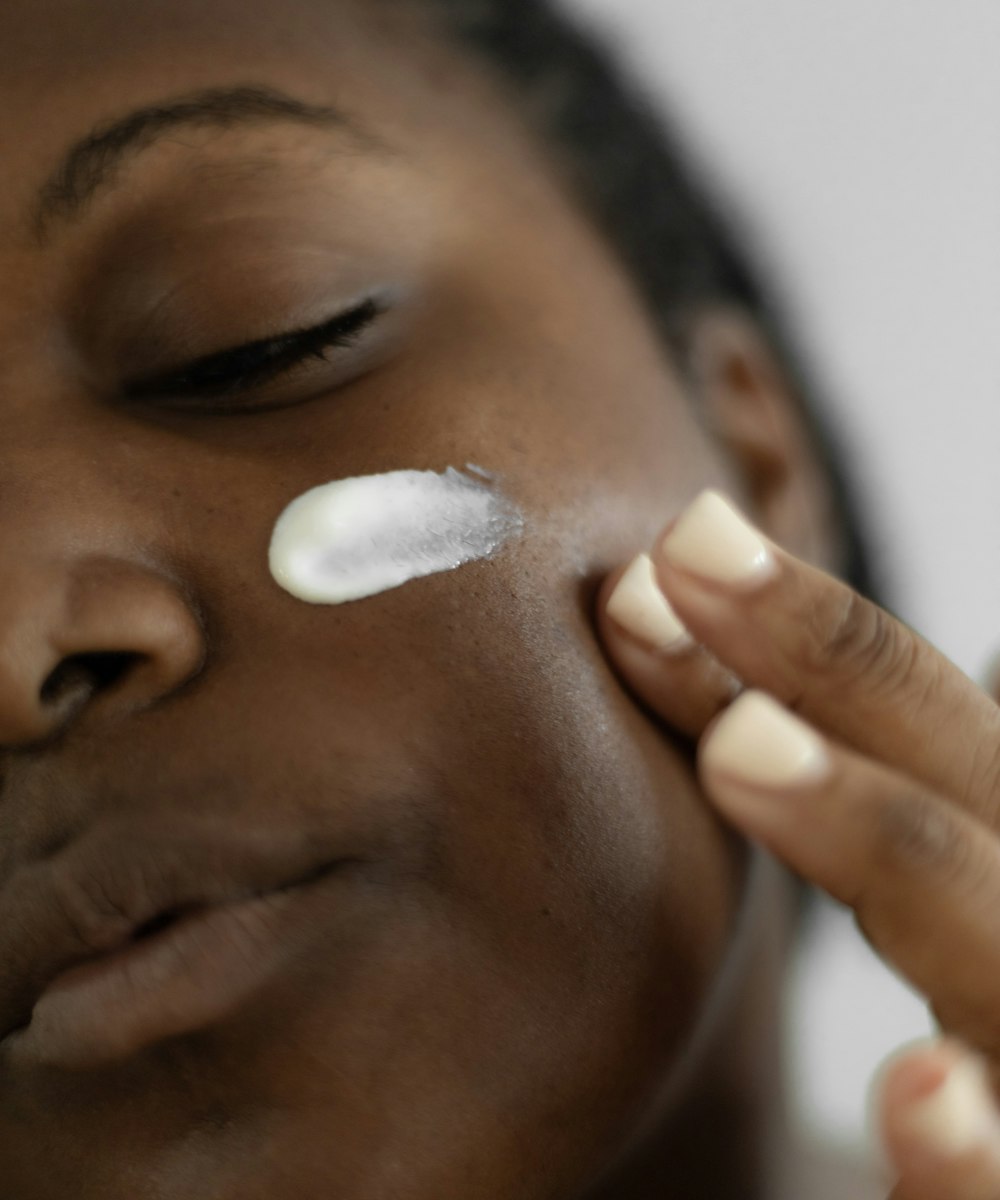 A person smoothing cream onto their cheek