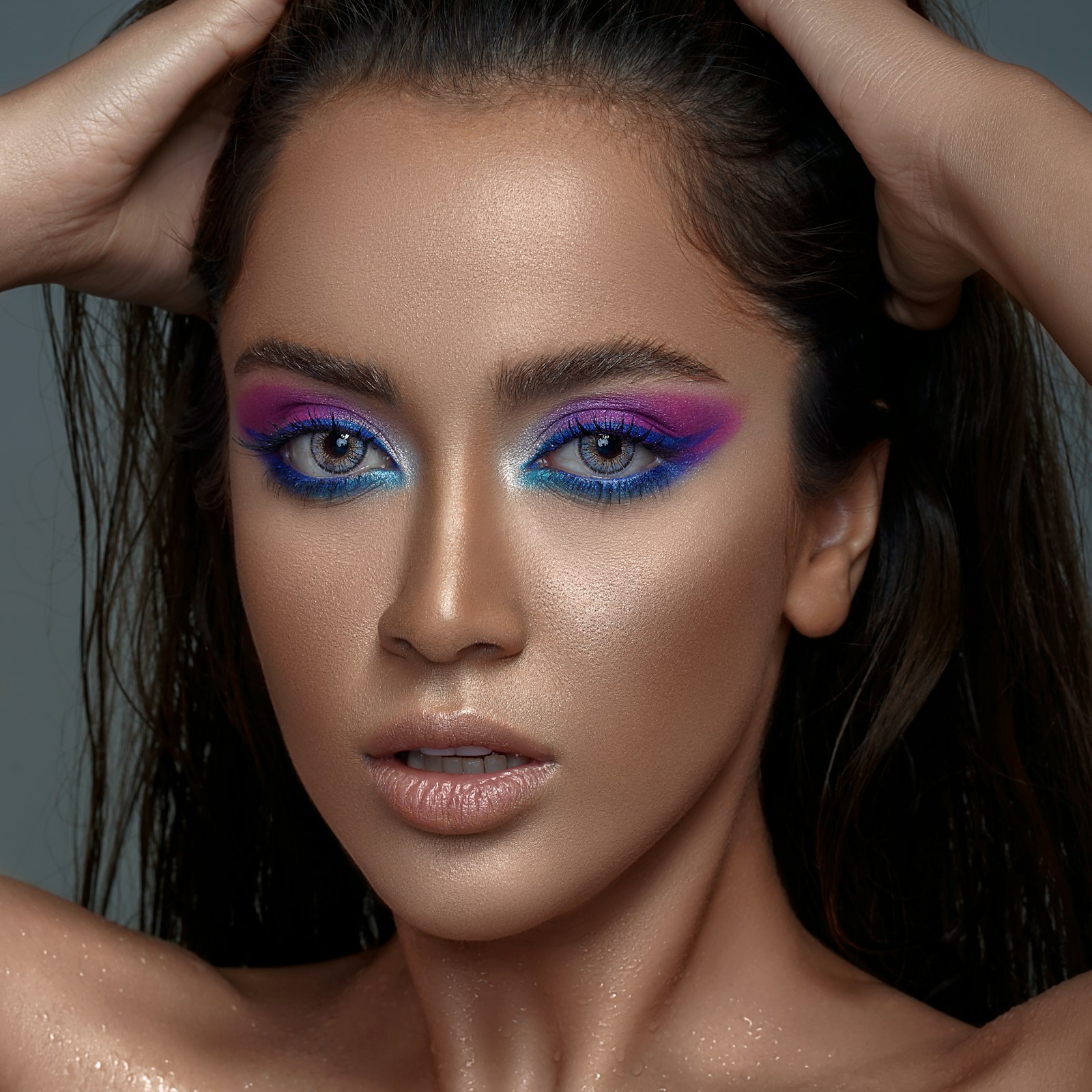 A model wearing bold electric-blue and magenta graphic eye makeup