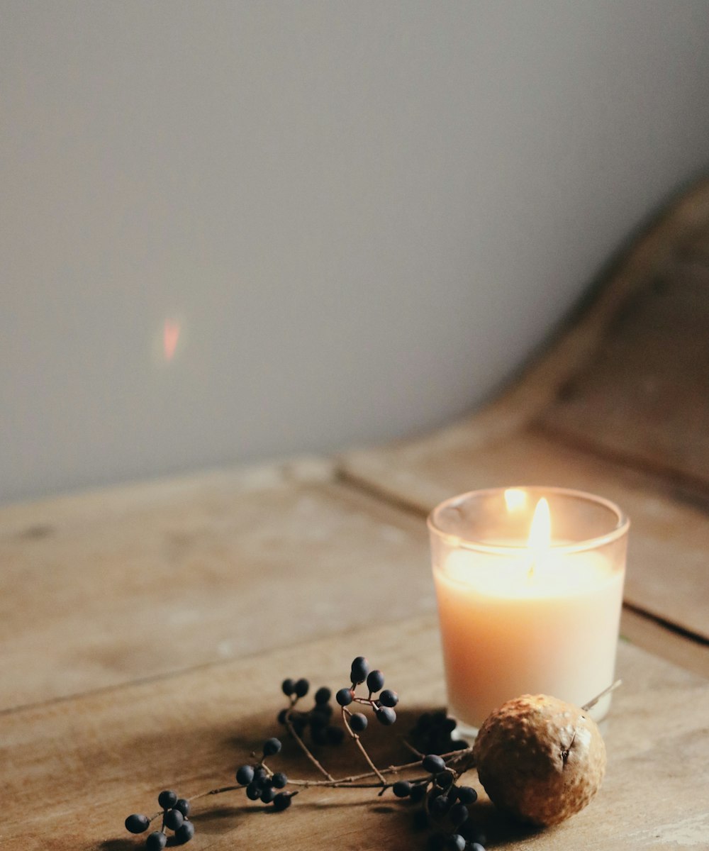 A candle and dried botanicals in warm, low light