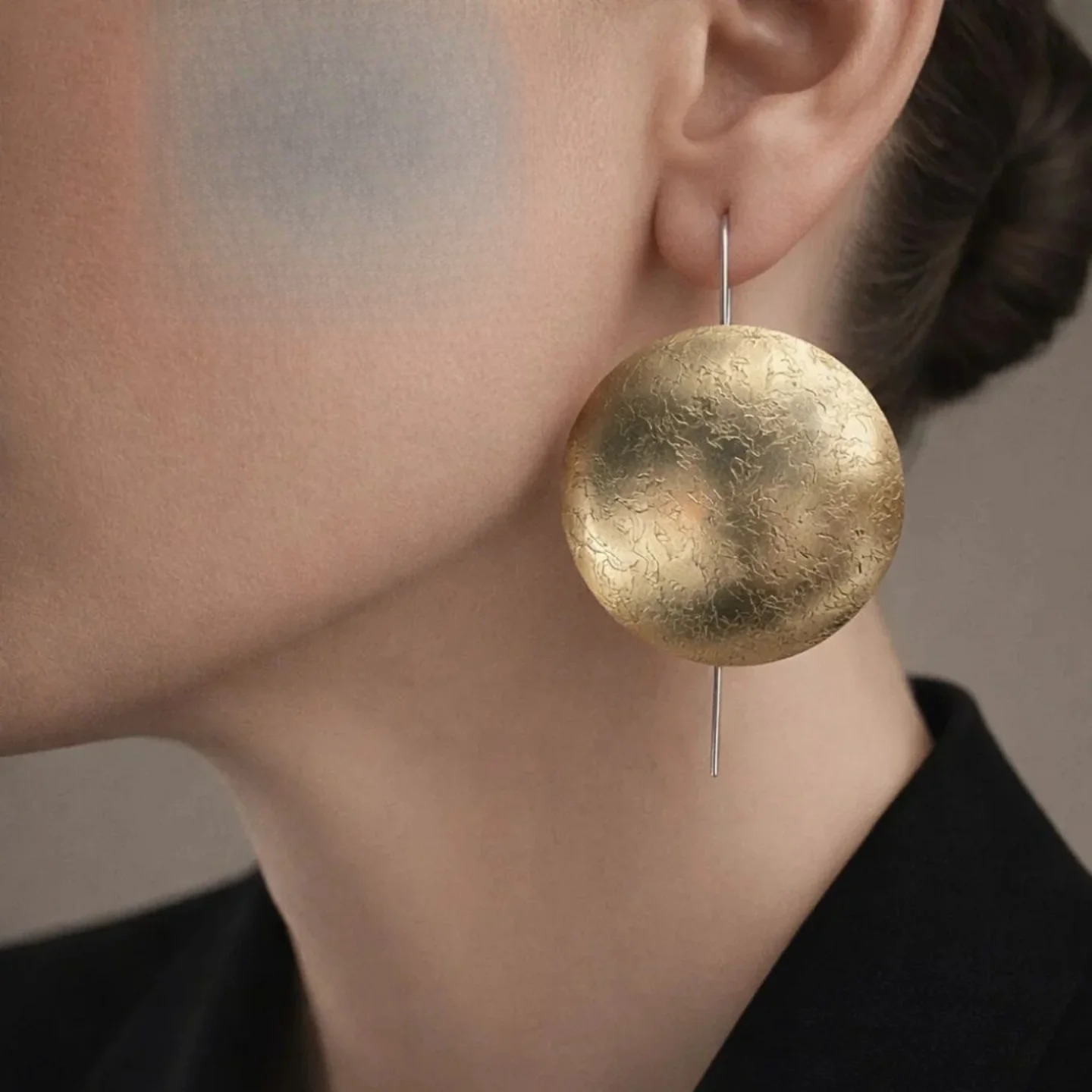 A large hammered gold disc earring