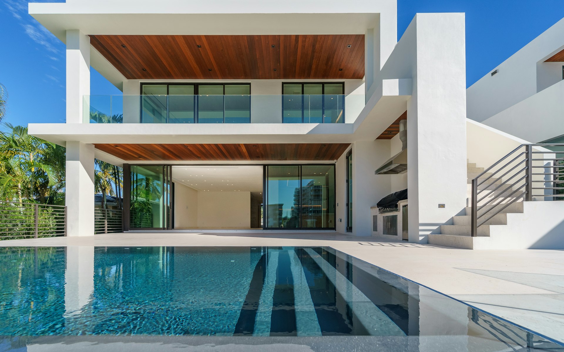 Exterior of 14 Lautner Drive at dusk, a glass-and-stone modern residence with warm interior lighting.