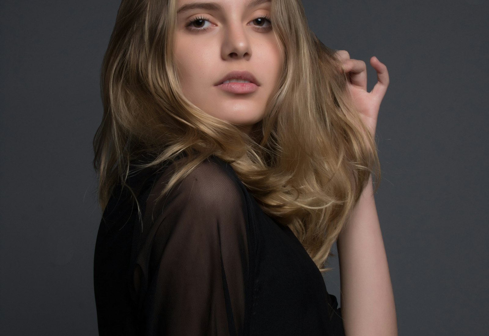 A model with glossy, dimensional balayage styled in soft waves at Lumière Hair Studio