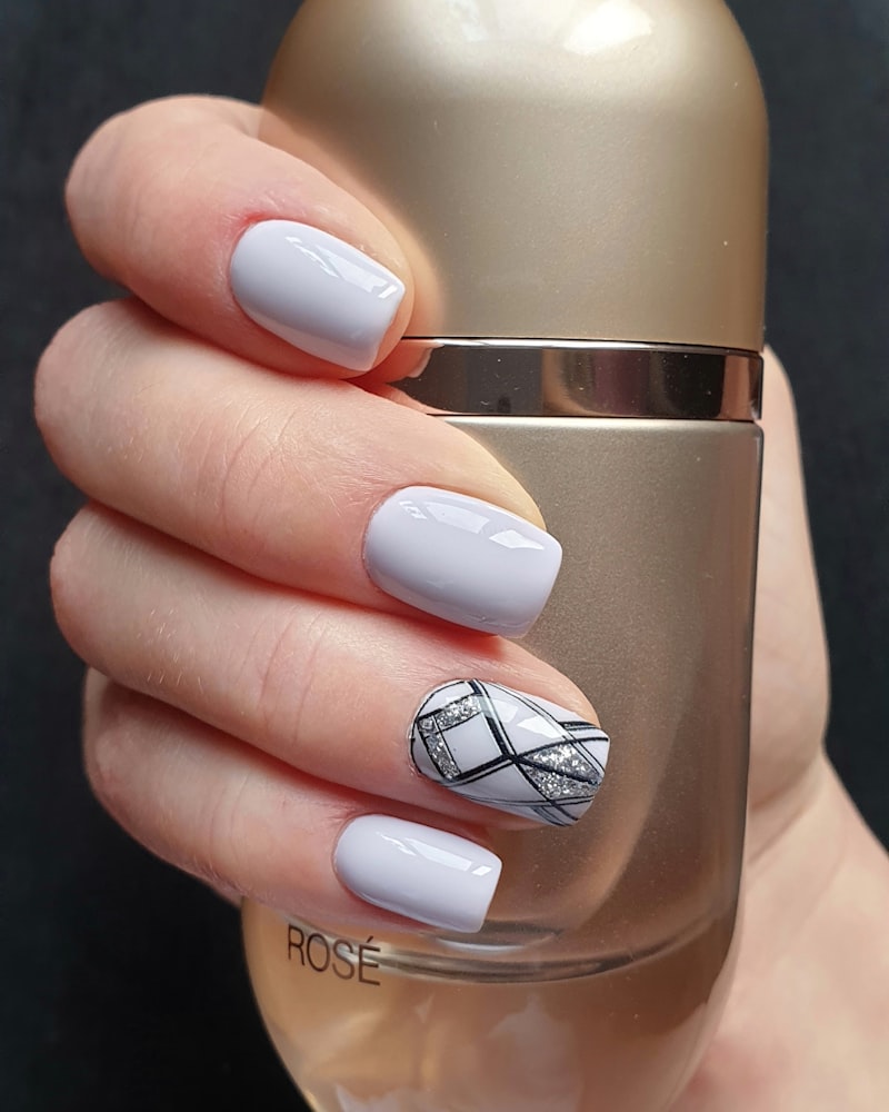 Soft lilac nails with a glossy gel finish and a geometric stained-glass accent