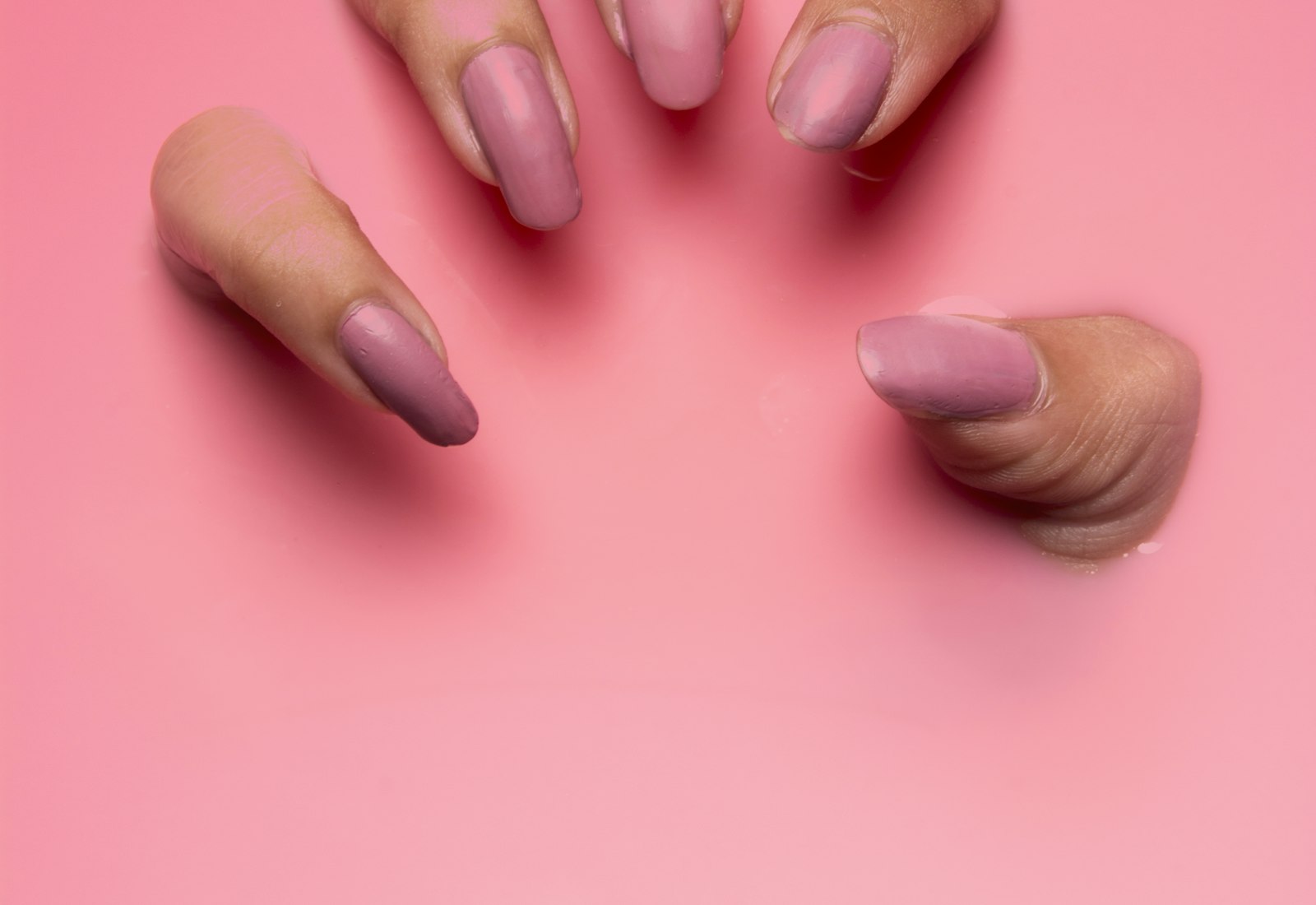 Freshly painted glossy coral gel manicure resting on a soft towel at Polished Nail Lounge