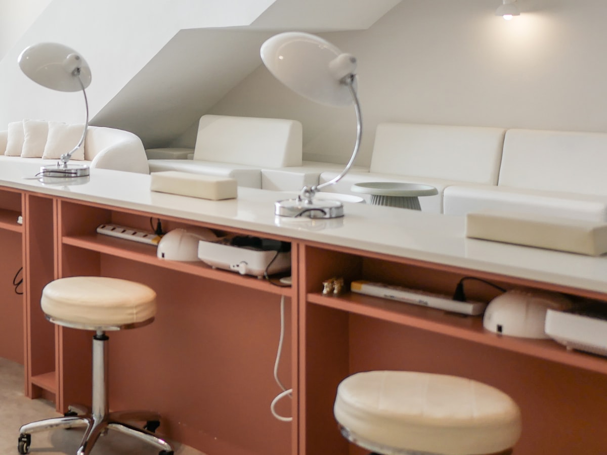 The bright, plant-filled interior of Polished Nail Lounge with blush pink seating and a colour wall