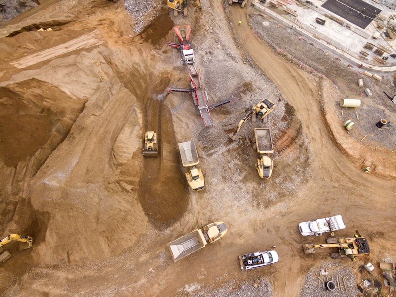Aerial view of an active excavation site with bulldozers and dump trucks moving earth