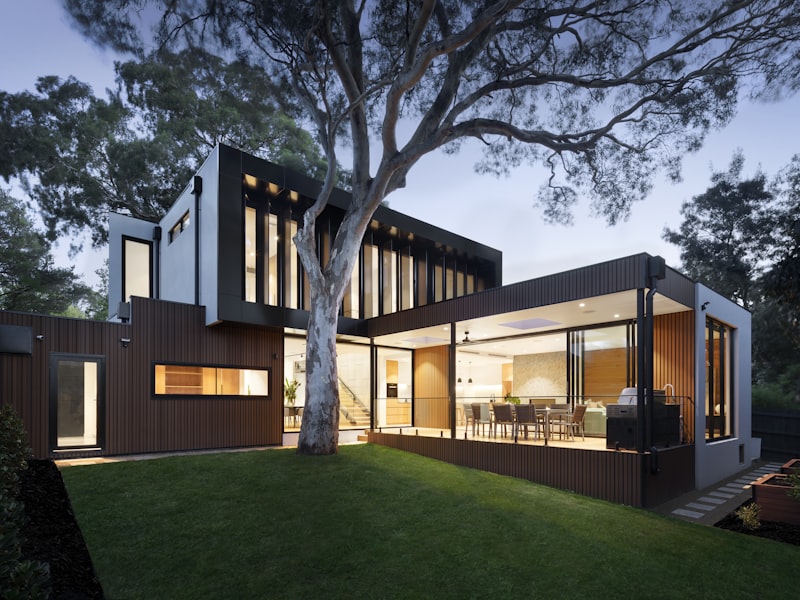 Modern timber-clad family home glowing at dusk with floor-to-ceiling glass