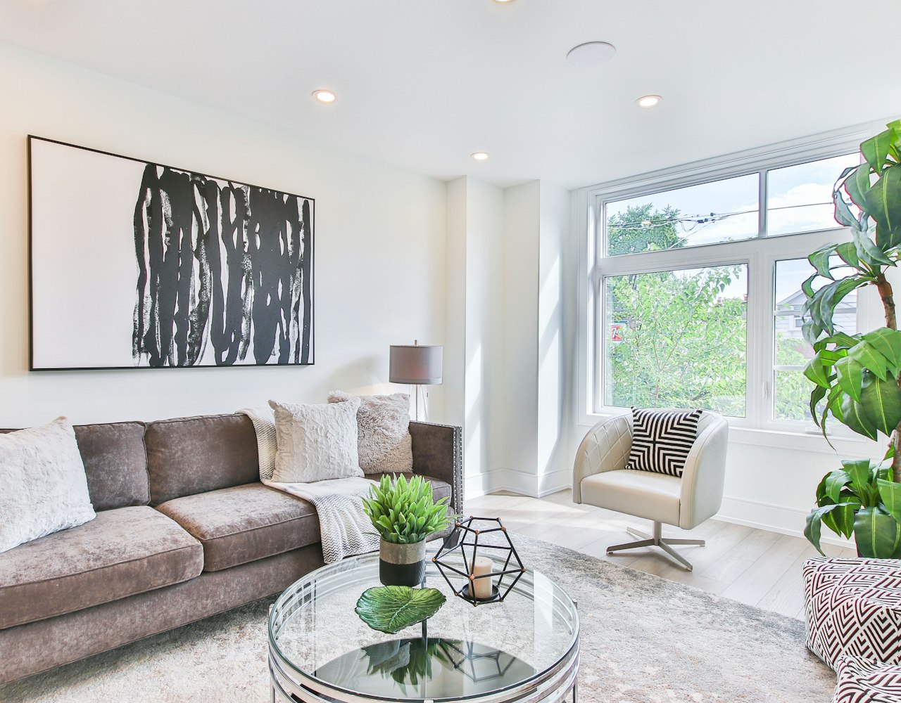 Bright, freshly cleaned living room with a glass coffee table, plush sofa and sunlit window