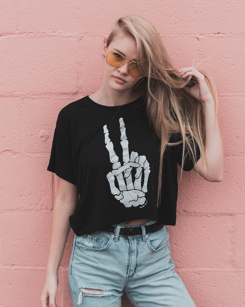 Editorial fashion portrait of a woman in tinted sunglasses against a pink wall