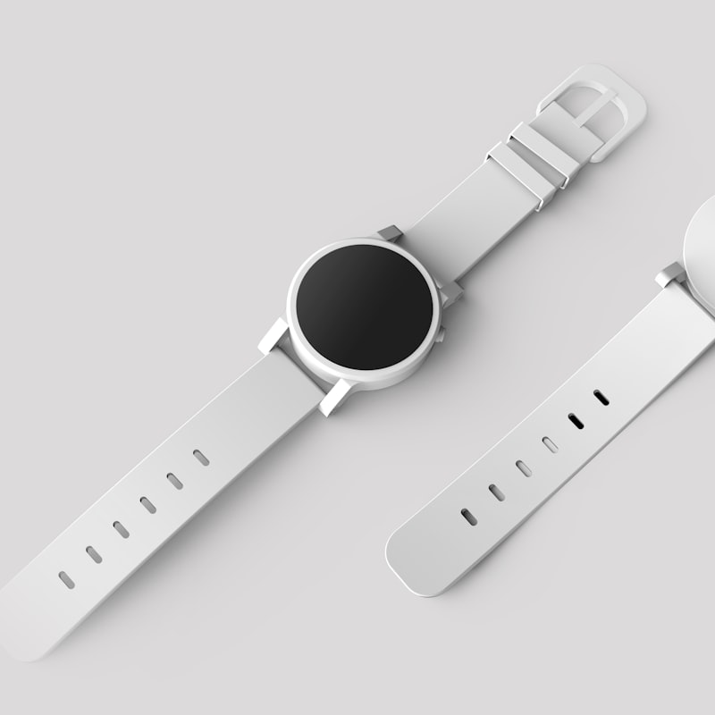 Two white minimalist smartwatches arranged on a pale grey backdrop