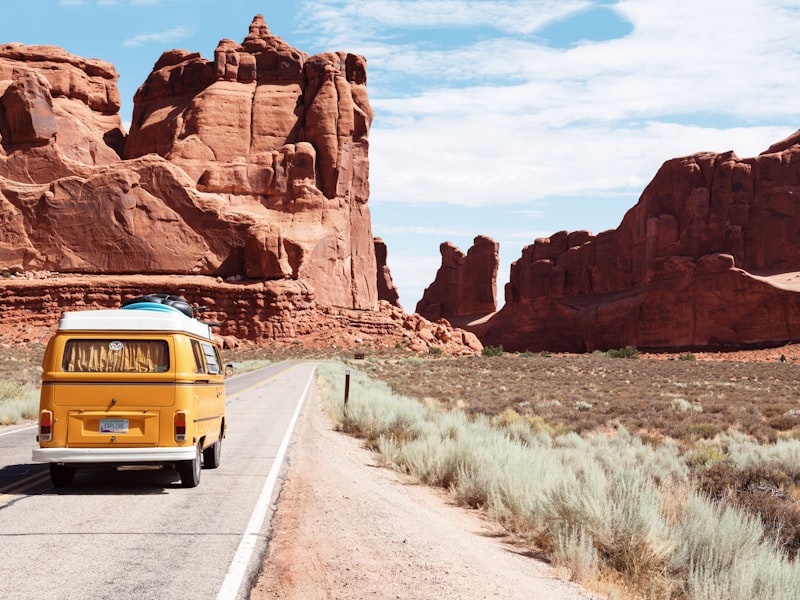 Vintage camper van on a desert highway among red rock formations