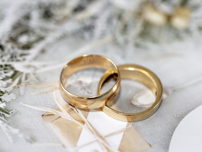 Two gold wedding rings resting on linen with soft greenery