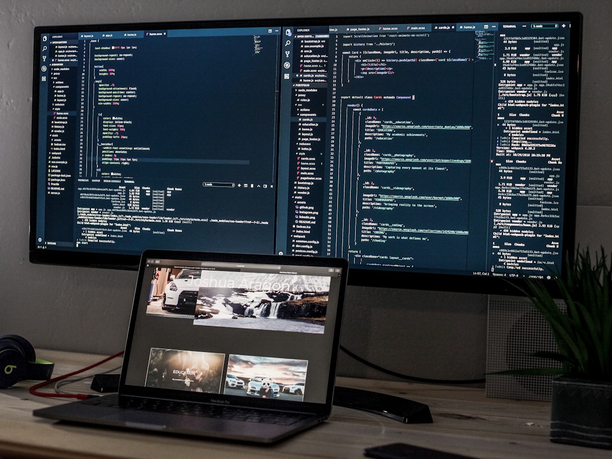 Dual monitor setup with a code editor and a creative portfolio open at night