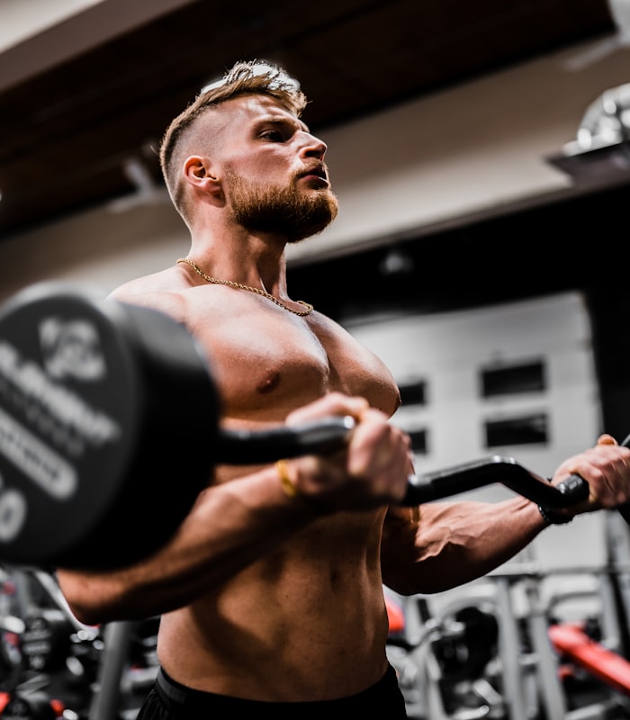 Client James performing a barbell curl in the gym