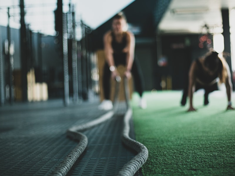Athletes training with battle ropes on the green turf lane