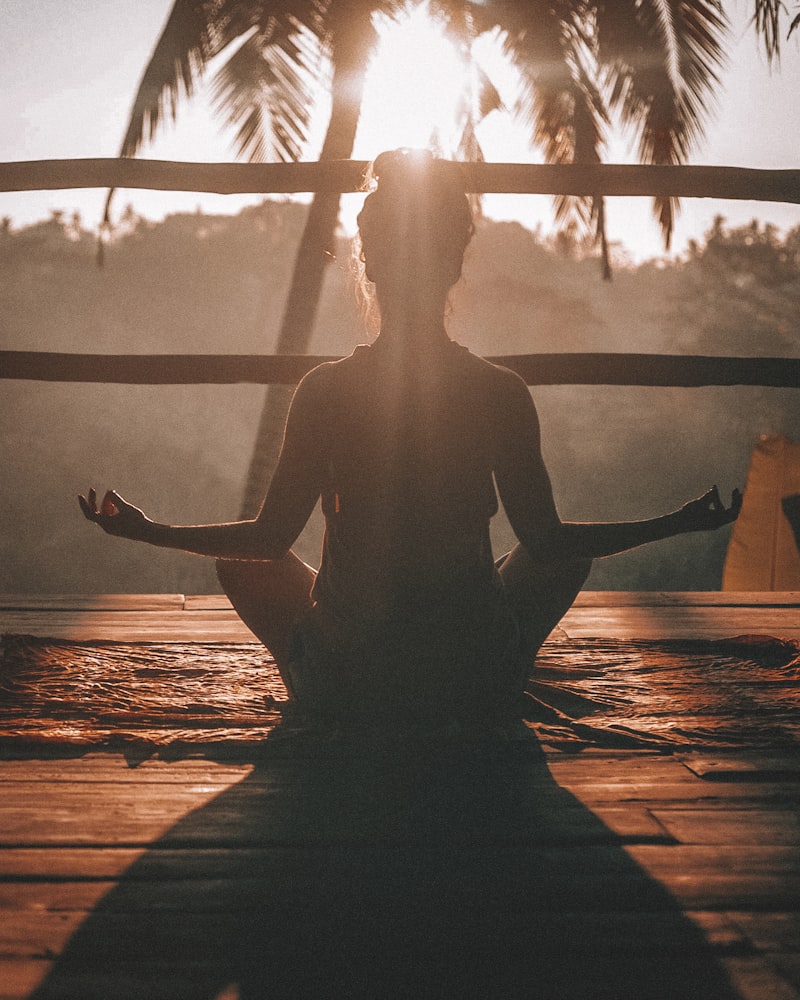 Silhouette of a person meditating cross-legged in warm golden light