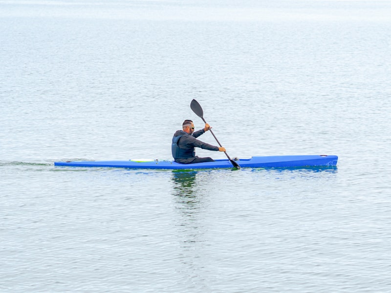 A kayaker paddling a slim sea kayak across calm open water