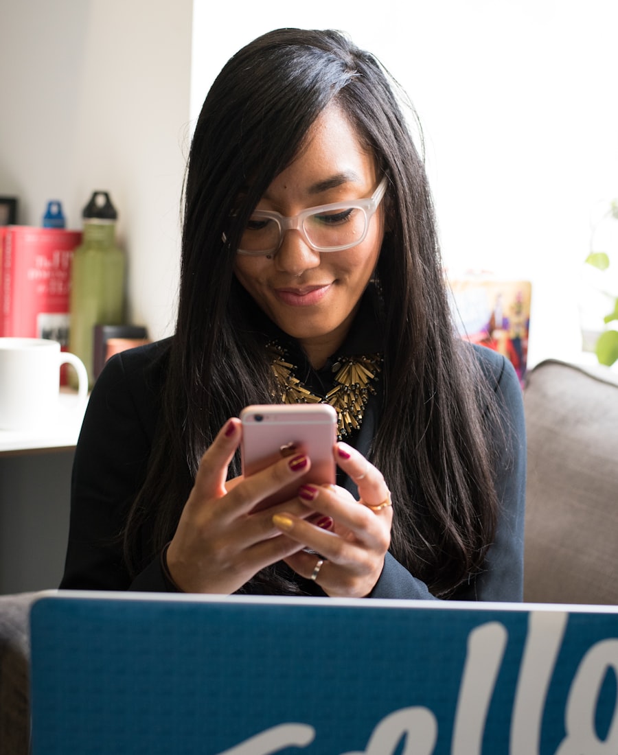Smiling woman in glasses concentrating on her phone in a bright room
