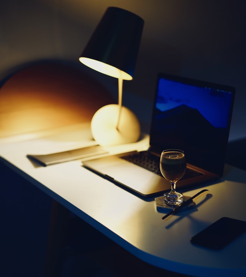 A warm pendant lamp casting a golden glow over a desk at dusk