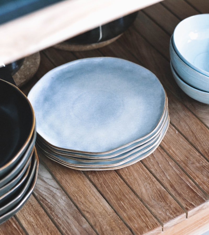 A stack of speckled blue-grey ceramic plates and bowls on a wooden surface