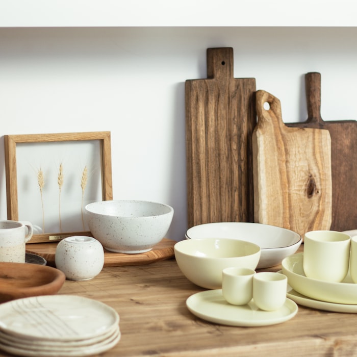 A shelf styled with ceramic bowls, wooden chopping boards and a framed print