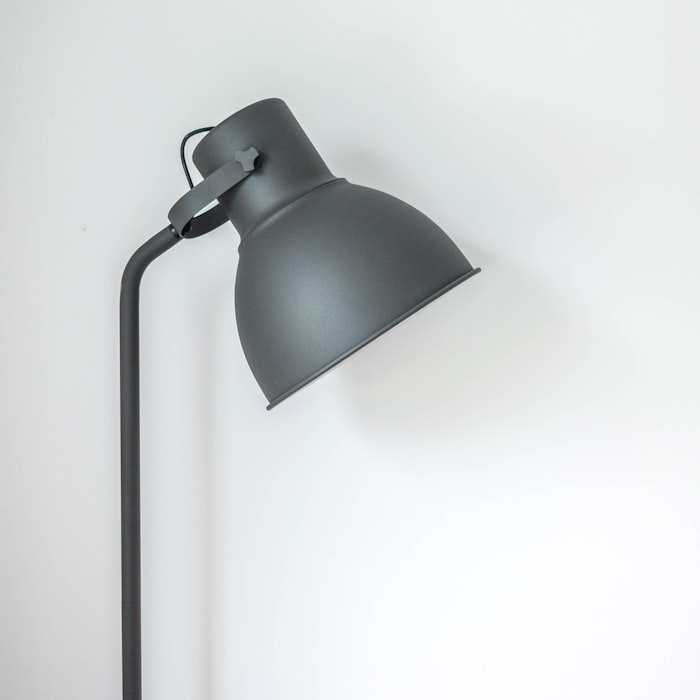 A matte charcoal angled task lamp against a plain white wall