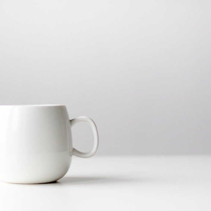 A single rounded white ceramic mug on a clean, pale surface
