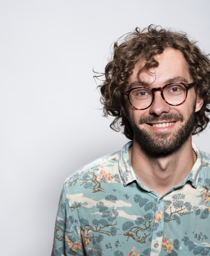 Portrait of Theo Marquez, host, smiling with curly hair and glasses