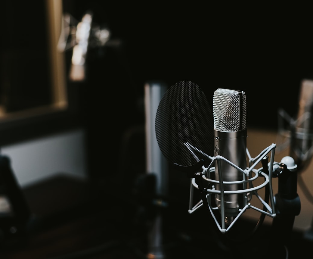 Condenser microphone with a pop filter set up in a dimly lit recording studio
